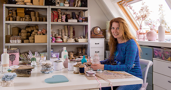 Irene die aan haar werktafel zit met accessoires om haar heen