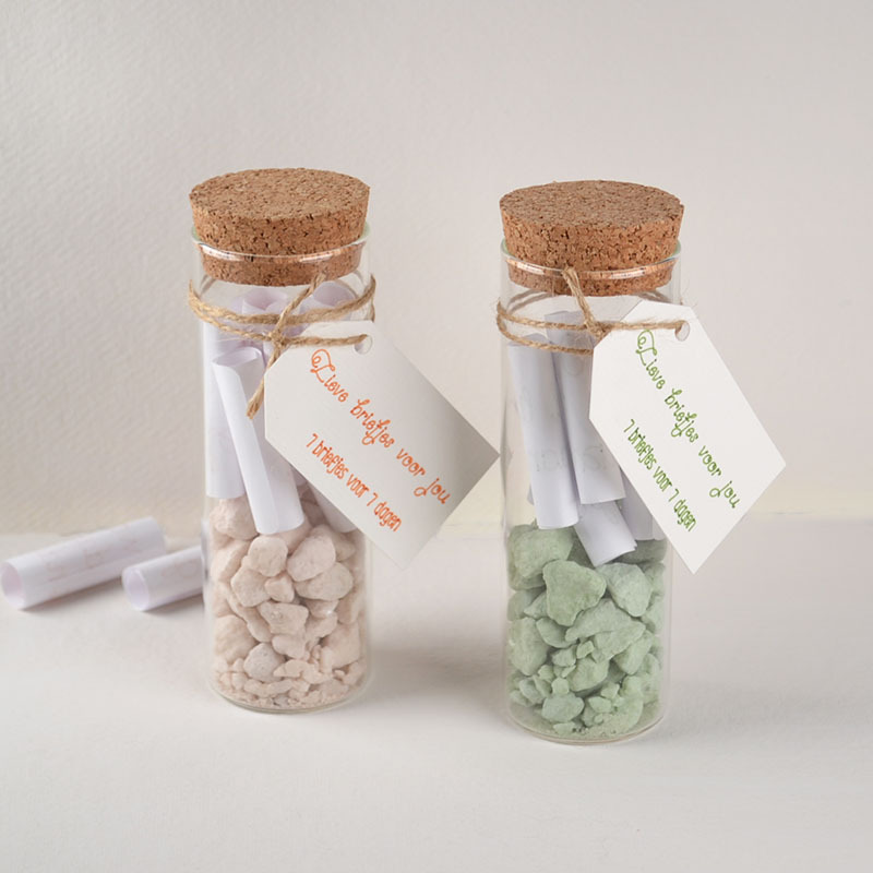 Twee glazen buisjes met lieve opgerolde briefjes en gekleurde steentjes
