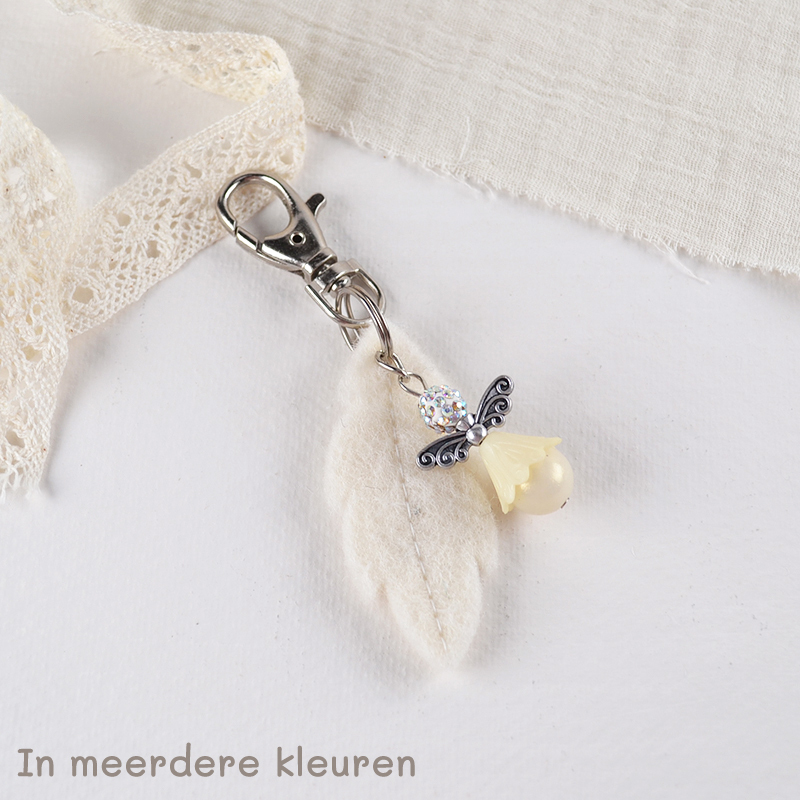 Sleutelhanger met ivoorkleurig engeltje, glinsterende kralen en zacht viltveer – een klein lichtpuntje voor onderweg.