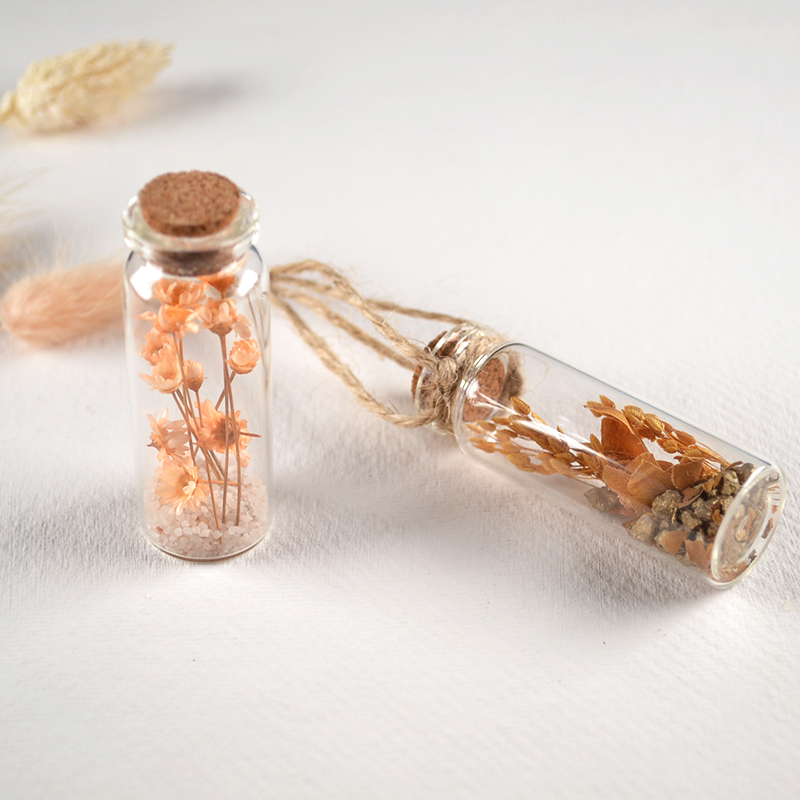 Twee kleine glazen flesjes met droogbloemen, kurk en jute touw
