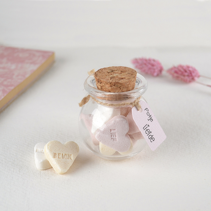 Glazen potje met kurk, gevuld met snoephartjes en label “Potje liefde” – zoet presentje voor elk moment