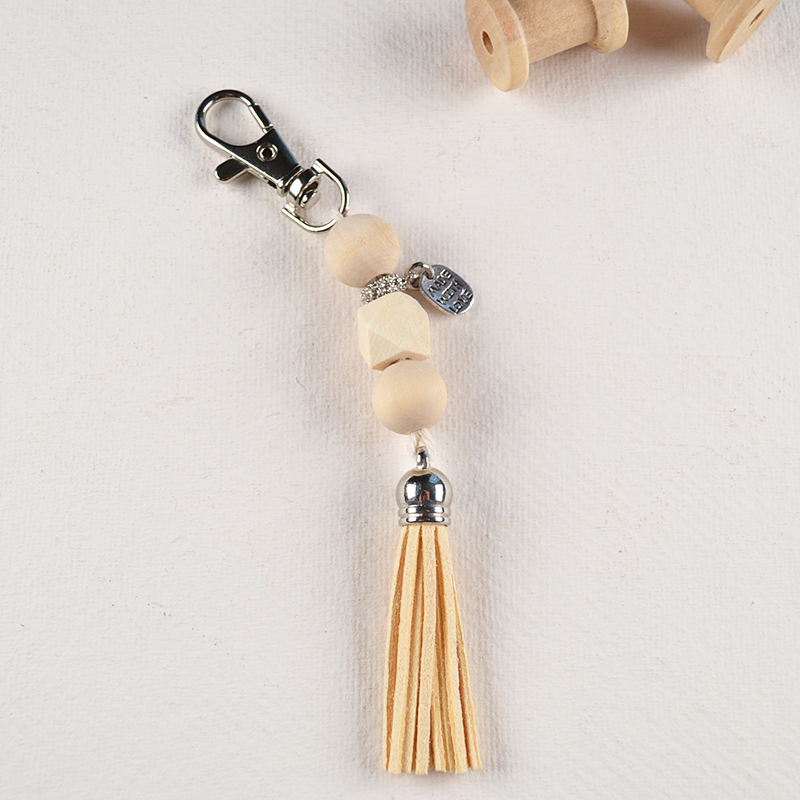 Boho sleutelhanger met houten kralen, zilverkleurige details en crèmekleurig kwastje.