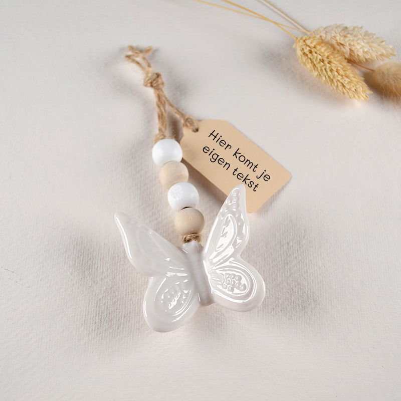 Hanger met witte keramieken vlinder, houten kralen en label met eigen tekst. kaarthanger-houder-kaart-ster-kralen.jpg ALT: Pluchen ster met houten kralen als kaarthanger met koperen clip.