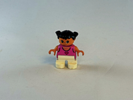 Meisje met witte broek, roze shirt met hartje erop en zwart haar Duplo