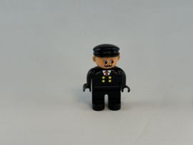 Man met snor, zwart pak en pet Duplo