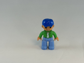 Man met licht blauwe broek, groen overhemd en blauwe pet Duplo