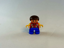 Meisje met blauwe broek, rood gele trui met bloemen erop en bruin haar Duplo