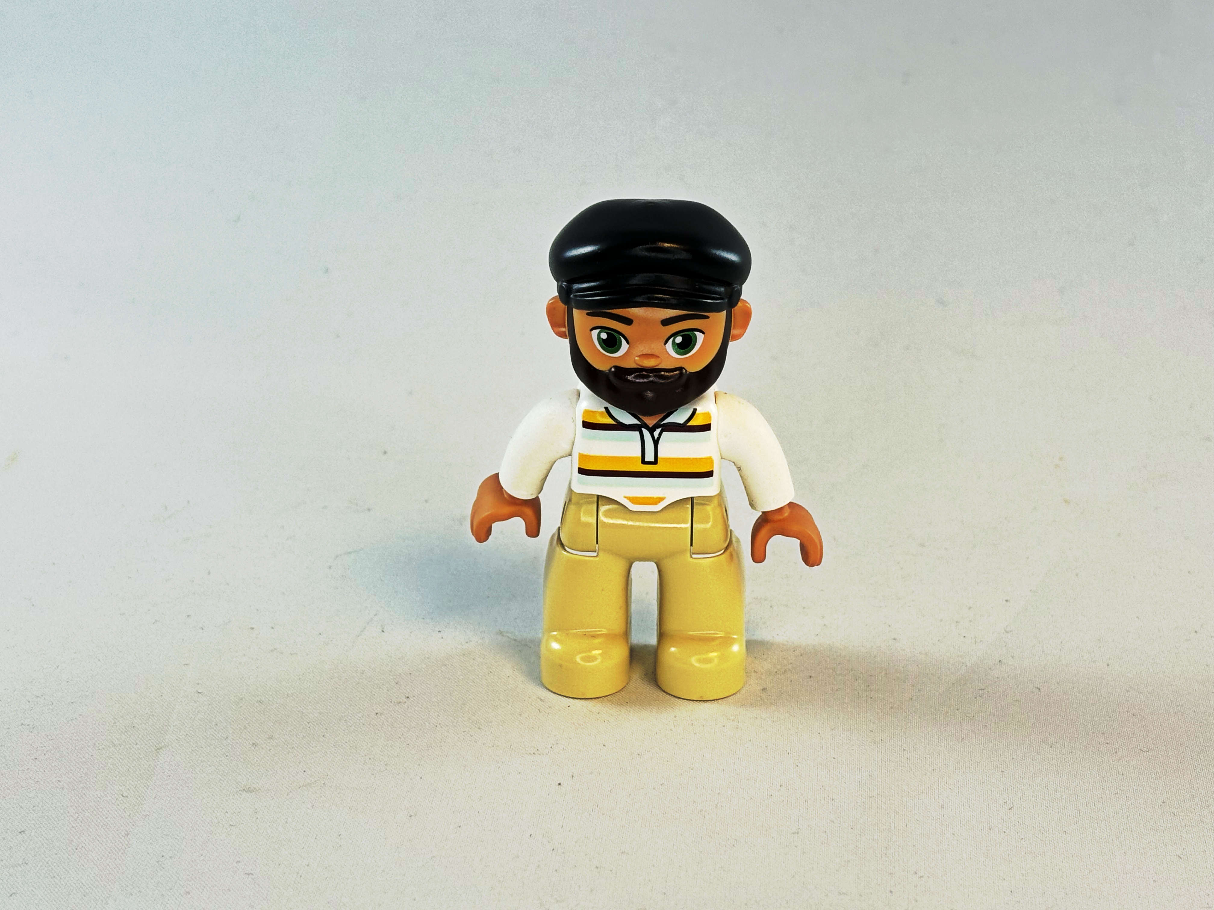 Man met beige / witte kleding en zwarte pet Duplo