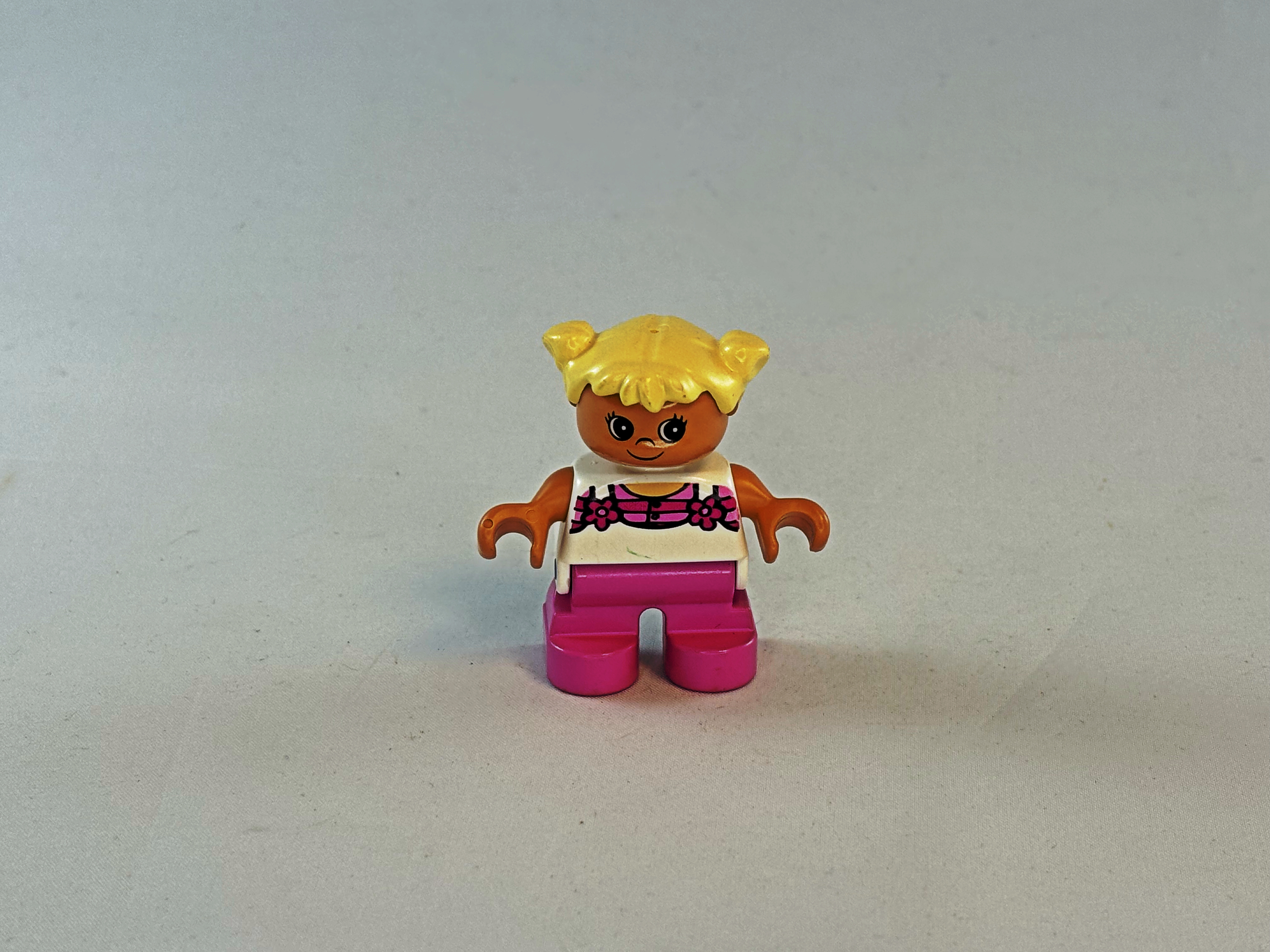 Meisje met roze broek, wit shirt en blond haar Duplo