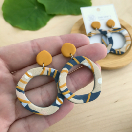 Organisch ronde statement oorbellen met abstract patroon in navy en okergeel, handgemaakt van klei (met rvs oorstekers)