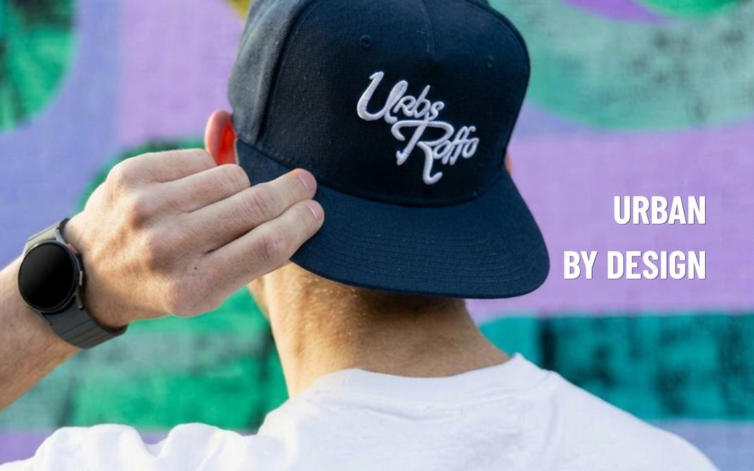 Navy Blue Urbs Roffa snapback pet met wit geborduurd logo, gedragen voor een kleurrijke street art muur.