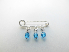 Zilveren baby speld met 3 blauwe ogri ai kraaltjes.