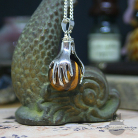 Spiritual necklace of two hands holding a Tiger Eye sphere