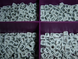 Mooie witte letterkralen met zwarte letters in de vorm van een blokje