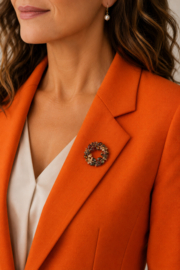 Goudkleurige bloemenkransbroche met gekleurde steentjes