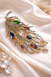 Goudkleurige veerbroche met gekleurde steentjes
