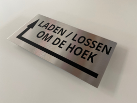 RVS deurplaatje KLEIN, opschrift "LADEN / LOSSEN OM DE HOEK"  + pijl linksom 18x9cm