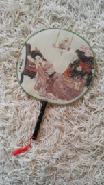 Mooie traditionele handwaaier van stof met Chinees tafereel en rood klosje