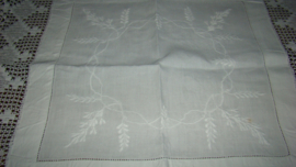 Vierkant wit geborduurd tafelkleedje met gehaakte rand.