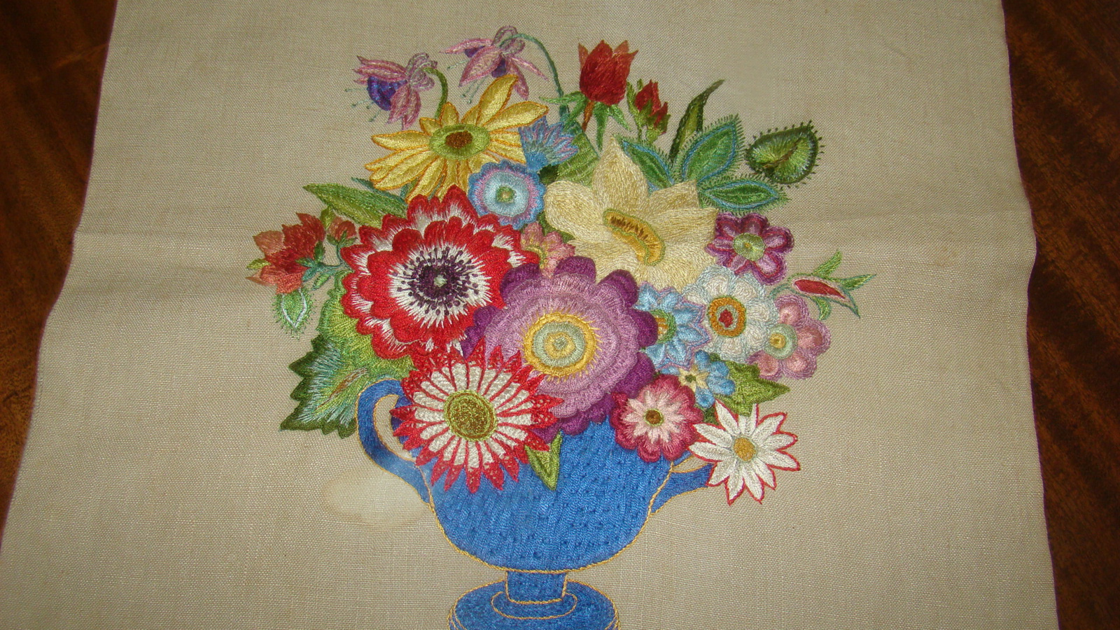 Geborduurde vaas met bloemen op linnen.