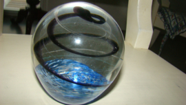 Grote presse-papier helder glas met zwarte spiraal en blauwe ondergrond.