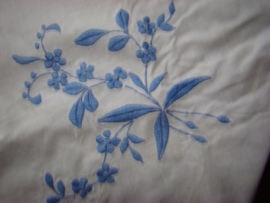 Wit geborduurd kleedje met blauwe bloemen.