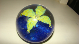 Presse-papier met blauwe ondergrond en gele bloem.