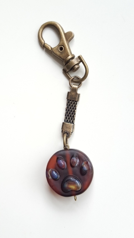 Bruine pootjeskraal aan bronskleurige sleutelhanger