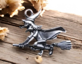 Metalen bedel van een heks op een bezemsteel, antiek zilverkleur afm. 37 x 30mm, oogje c.a. 2mm