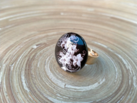 Goudkleurige ring met zwarte bloemen cabochon. Verstelbaar