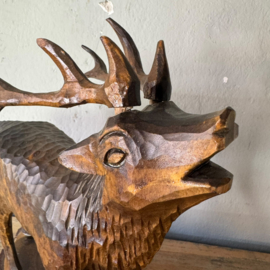 Hand-carved wooden deer on a pedestal