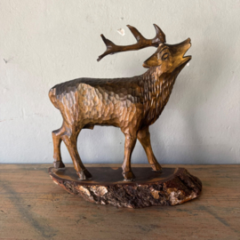 Hand-carved wooden deer on a pedestal