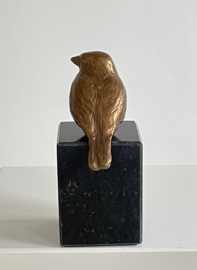 Bronzen vogeltje op steen