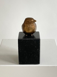 Bronzen vogeltje op steen