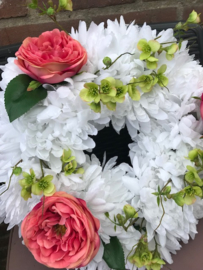 Bloemenkrans gevuld met witte chrysanten, zijde bloesem, zijde pioenrozen