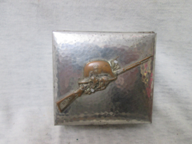 German metal little box with badge on top. Duits metalen doosje, met op de deksel een embleem van een Duitse helm met een Mauser K-98. leuk origineel opbergdoosje.