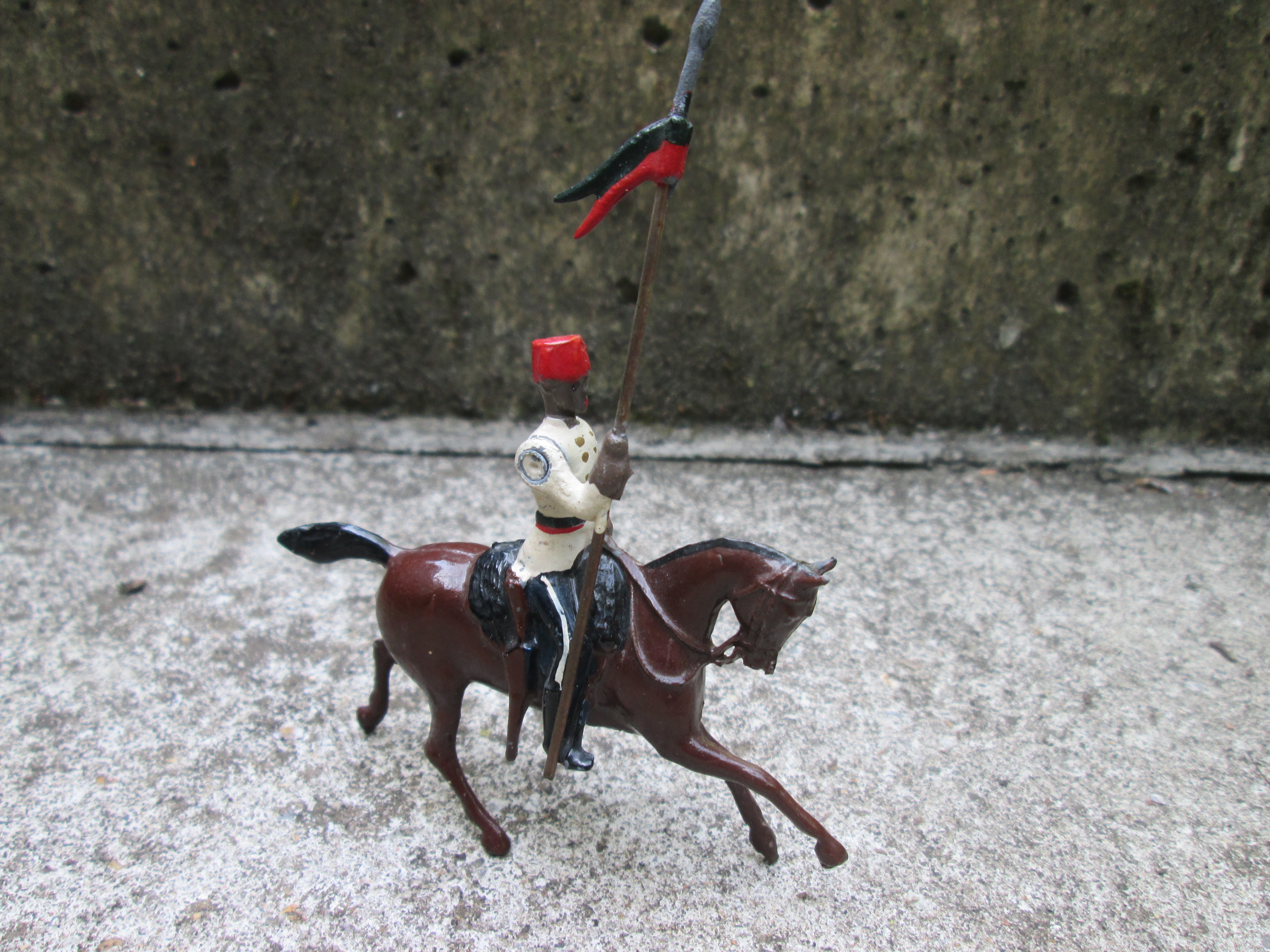 British tin toy from BRITAIN. Tinnen soldaatje koloniale ruiter met vlag bewegende arm, gemerkt.