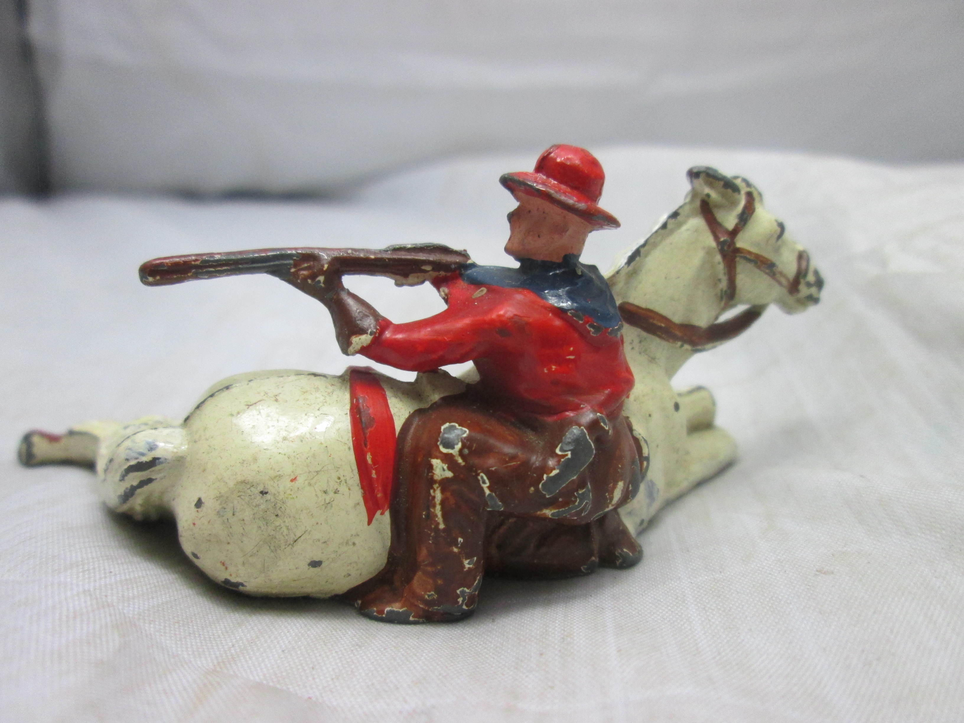 Tin toy, Britain made. tinnen cowboy die bescherming zoekt achter zijn paard leuk tafereel.