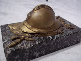 Press-papier, French miniature helmet on marble base. Franse miniatuurhelm met infanterie embleem in brons, liggend op vaandel gemonteerd op een marmeren voet, zeer decoratief.