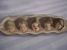 Curieus werkje van gips, stelt een boon voor met 5 erwten in de vorm van een gezichtje. de middelste heeft een lievenheersbeestje op zijn neus en is dus wakker.