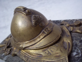 Press-papier, French miniature helmet on marble base. Franse miniatuurhelm met infanterie embleem in brons, liggend op vaandel gemonteerd op een marmeren voet, zeer decoratief.