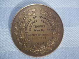 British medal between wars. Bayonet fencing trophy 1934. medal was presented by Lt. Col. Bellamy, TD  to  Lt. N.B. Deeks.. Mooie penning met randschrift. curieus ding. doorsnee 4 cm. in originele doos.
