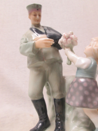 German statue made of china, nicely marked. Porseleinen beeld ( vaas) van een Duitse soldaat die gewond uit de Eerste Wereldoorlog terug komt en bloemen krijgt overhandigd. genummerd en gemerkt Zeldzaam stuk. TOP 19 cm..