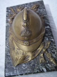 Press-papier, French miniature helmet on marble base. Franse miniatuurhelm met infanterie embleem in brons, liggend op vaandel gemonteerd op een marmeren voet, zeer decoratief.