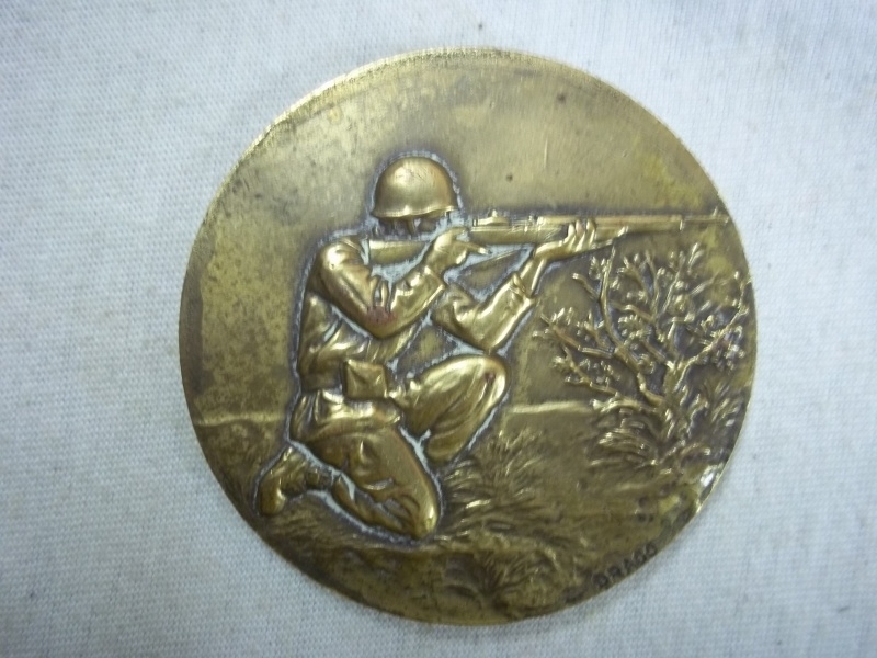 Military plaque shooting soldier, made by Drago.Franse penning met daarop een schietende soldaat, brons, gemaakt bij Drago.