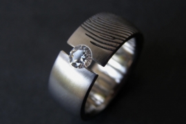 Titanium ring met openzetting en witte steen.