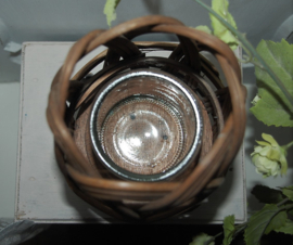 Rotan kandelaartje op drie houten pootjes. Binnenin een glas voor een kaars.