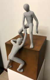 sculptuur man helpende hand op cortenstaal kubus