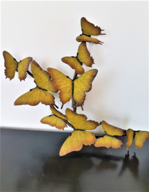 Negen bronzen gele vlinders op tak
