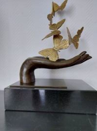 Zes vlinders in een hand brons beeld